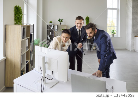 Corporate team discussing strategy at computer in bright office, analyzing data 135448058