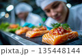 Food industry workers preparing fresh salmon fillets on a processing line in a hygienic seafood production facility 135448144