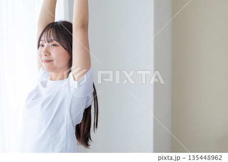 窓辺でストレッチをする若い女性 135448962