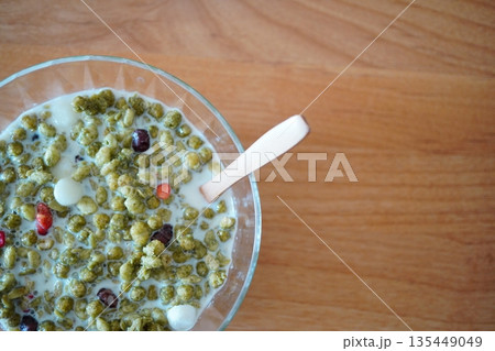 抹茶風味のシリアルにミルクを注いだ朝食シーン、木目テーブルに映えるナチュラルフード写真 抹茶風味のシリアルにミルクを注いだ朝食シーン、木目テーブルに映えるナチュラルフード写真 135449049