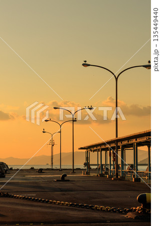 愛媛県八幡浜市の八幡浜港で、夕暮れ時の街灯と穏やかな海 135449440