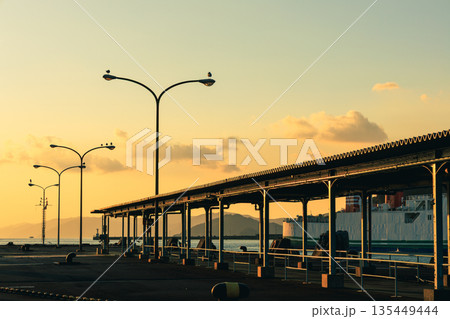 愛媛県八幡浜市の八幡浜港で、夕暮れ時の街灯と穏やかな海とフェリー 135449444