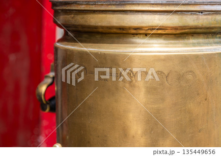 Vintage brass tea urn with engravings and warm ambiance Vintage brass tea urn with engravings and warm ambiance 135449656