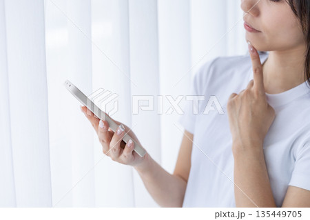 スマートフォンを持って考える若い女性 135449705