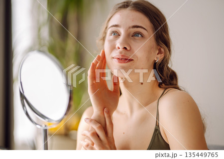 Young woman with problem skin looking into mirror. Concept of acne therapy, scars 135449765
