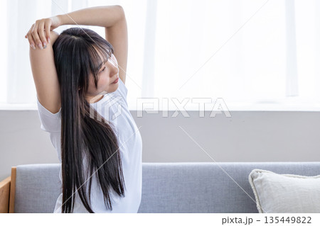 ソファーでストレッチをする若い女性 ソファーでストレッチをする若い女性 135449822