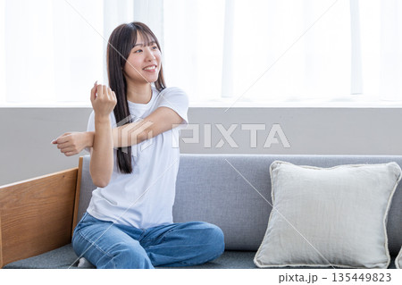 ソファーでストレッチをする若い女性 ソファーでストレッチをする若い女性 135449823
