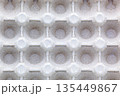 Repeating pattern of empty cells in a paper egg container. Macro shot of recycled cardboard texture. Concept of eco-friendly packaging, recycling, and rhythmic design 135449867