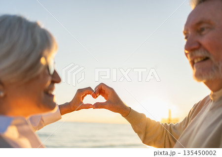 Love heart shape peace. Senior older couple making heart shape with their hands. Adult mature old husband wife showing heart sign. Happy pensioner family. I love you happy valentines day Love heart shape peace. Senior older couple making heart shape with their hands. Adult mature old husband wife showing heart sign. Happy pensioner family. I love you happy valentines day 135450002