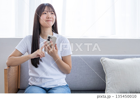 スマートフォンを使う若い女性 スマートフォンを使う若い女性 135450010