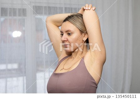 Woman Doing Stretching Exercises at Home Near Window During Daytime Woman Doing Stretching Exercises at Home Near Window During Daytime 135450111