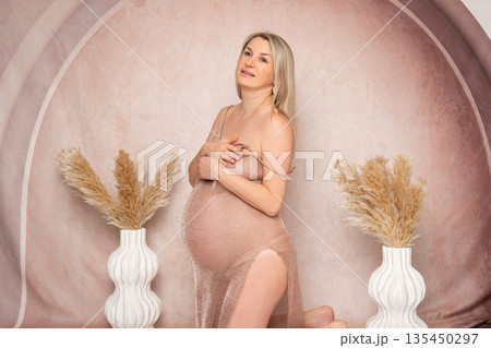 38 week, Artistic studio portrait of a pregnant woman posing nude with soft drapery. Elegant composition, calm mood and natural beauty. Concept of femininity, maternity and body positivity. 38 week, Artistic studio portrait of a pregnant woman posing nude with soft drapery. Elegant composition, calm mood and natural beauty. Concept of femininity, maternity and body positivity. 135450297