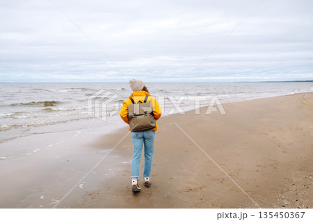 Attractive woman on a windy cold beach. Travel, nature concept. 135450367