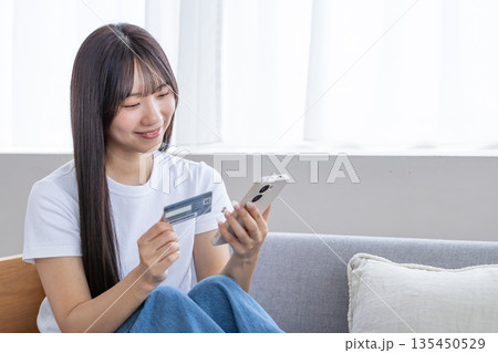 スマホとクレジットカードを持つ若い女性 スマホとクレジットカードを持つ若い女性 135450529