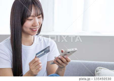 スマホとクレジットカードを持つ若い女性 スマホとクレジットカードを持つ若い女性 135450530