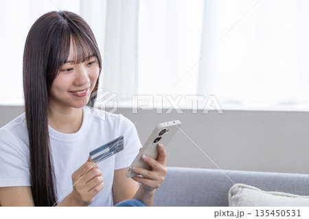スマホとクレジットカードを持つ若い女性 135450531