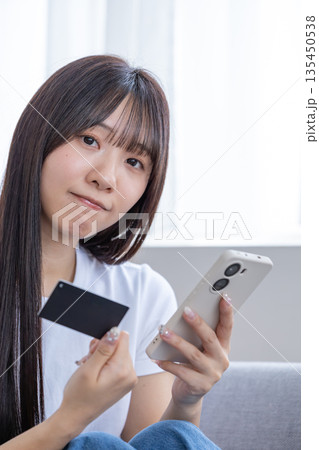 スマホとクレジットカードを持つ若い女性 135450538