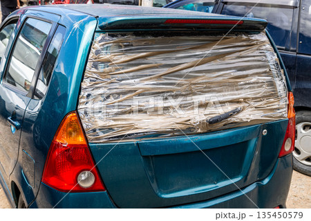 Car with broken rear window covered with clear tape 135450579