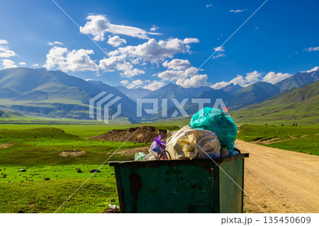 Trash bin filled with garbage bags in scenic mountain valley 135450609