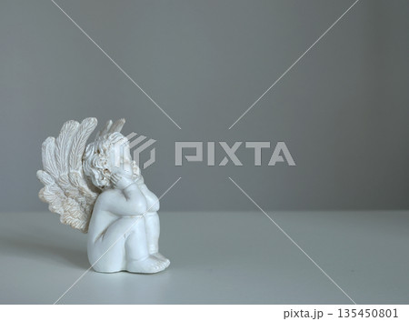 White ceramic angel figurine on white background for design. Faith, symbols, and traditions. 135450801