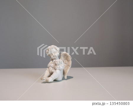 White ceramic angel figurine with animal dog on white background for design. Faith, symbols, and traditions. 135450803