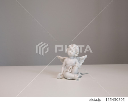 White ceramic angel figurine on white background for design. Faith, symbols, and traditions. 135450805
