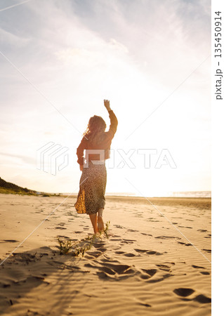 Beautiful woman on the beach in cold weather enjoying time in the sunset. Lifestyle, adventure. 135450914