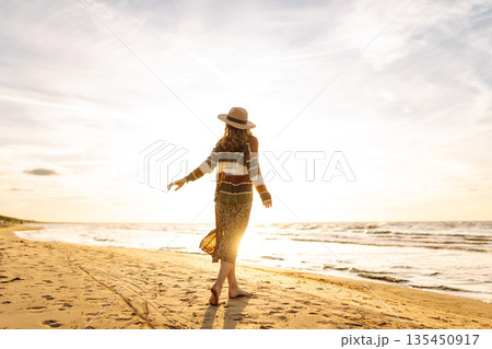 Beautiful woman at the windy spring day relaxing on coast. Carefree lady looking at the sunset. Beautiful woman at the windy spring day relaxing on coast. Carefree lady looking at the sunset. 135450917