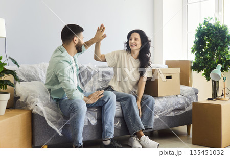 Happy couple moving into new home apartment, young people give high five Happy couple moving into new home apartment, young people give high five 135451032