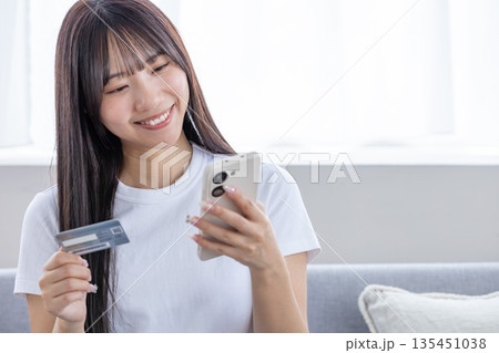スマホとクレジットカードを持つ若い女性 135451038