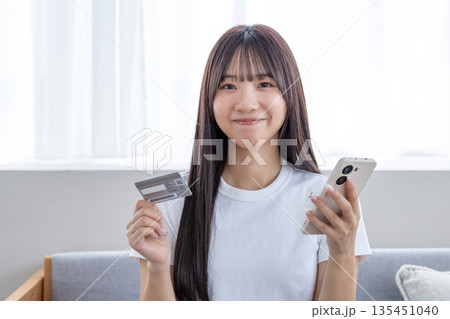 スマホとクレジットカードを持つ若い女性 スマホとクレジットカードを持つ若い女性 135451040