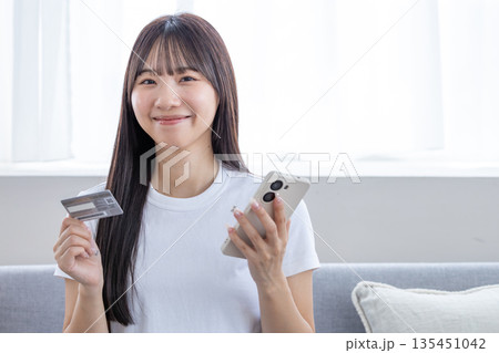 スマホとクレジットカードを持つ若い女性 スマホとクレジットカードを持つ若い女性 135451042