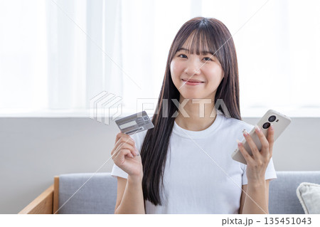 スマホとクレジットカードを持つ若い女性 135451043