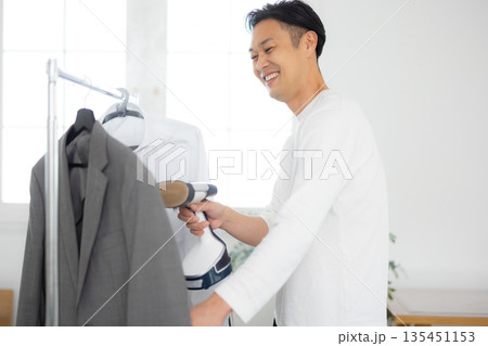 服にスチーマーをかける男性 135451153