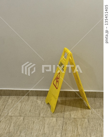 Wet floor sign on tile floor indoors, a concept of safety and caution in public spaces 135451405