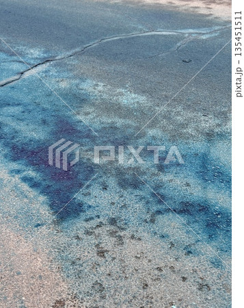 A Blue Chemical Stain On The Asphalt Of The Road, On Which Uneven Spots Of Bright Blue Liquid Are Visible, Accumulated In Puddles And Smeared On Faded Markings And Cracked Asphalt. 135451511