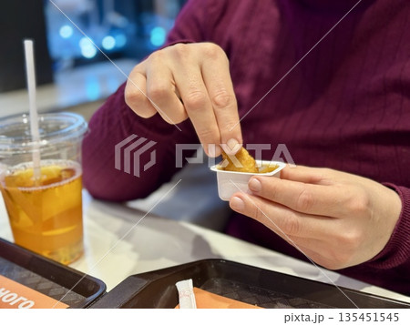 Woman Hand Holding Chicken Nugget Over Sauce, CloseUp Of Casual Eater In Maroon Shirt Dipping Golden Crispy Nugget Into HoneyMustard. Remote Worker Enjoying Quick food. Woman Hand Holding Chicken Nugget Over Sauce, CloseUp Of Casual Eater In Maroon Shirt Dipping Golden Crispy Nugget Into HoneyMustard. Remote Worker Enjoying Quick food. 135451545
