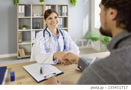 Handshake of happy doctor and patient at medical consultation in hospital Handshake of happy doctor and patient at medical consultation in hospital 135451717