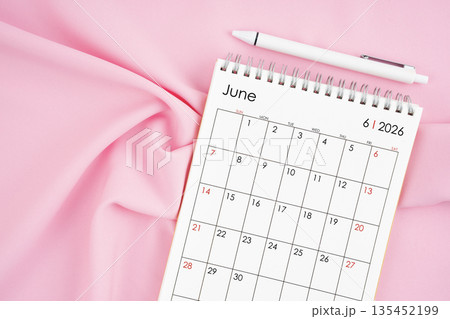 June 2026 month calendar and pen on pink fabric background. June 2026 month calendar and pen on pink fabric background. 135452199