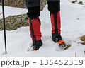 Hiker legs with crampons in snow 135452319