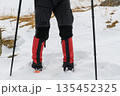 Hiker legs with crampons in snow 135452325