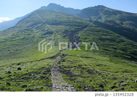 石畳の登山道と緑の丘に続く山の風景 135452328