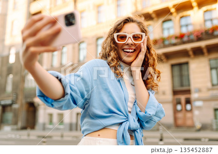 Beautiful woman traveler using phone, taking selfie, walking on the old town street. Blogging 135452887