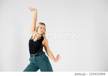 Young blonde dancer posing with hands joined and legs apart on white background Young blonde dancer posing with hands joined and legs apart on white background 135452909