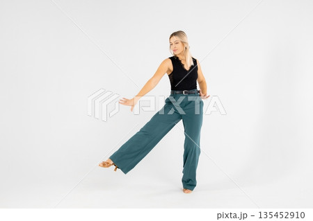 Young blonde dancer posing with hands joined and legs apart on white background Young blonde dancer posing with hands joined and legs apart on white background 135452910