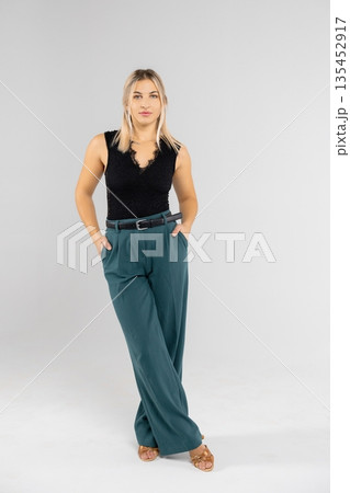 Businesswoman posing with hands in pockets in studio setting Businesswoman posing with hands in pockets in studio setting 135452917