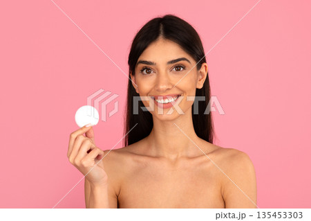 Young woman holding cotton pad in studio. Skincare and makeup removal concept 135453303