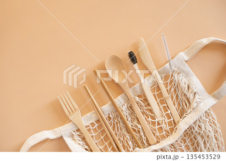 Eco friendly bag and bamboo cutlery set with toothbrush on beige background for green life and zero waste concept. Top view 135453529