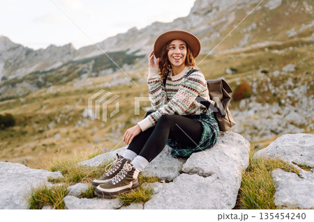 Happy woman stands on rocky terrain, gazing out at breathtaking landscape before her. Lifestyle. 135454240