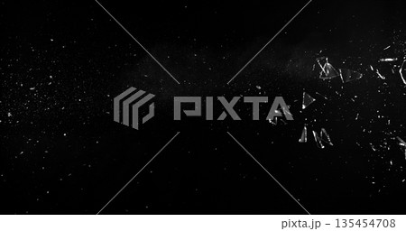 Side angle photo of flying shattered glass shards and dust isolated on black background. High detail debris explosion, perfect for VFX overlay, compositing, transitions or dramatic design elements. 135454708